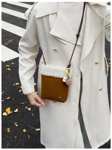 Détail du sac bandoulière d'hiver marron avec bordure en fourrure blanche et breloques