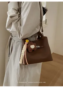 Detailed close-up of retro brown pebbled leather bucket bag with teddy bear charm
