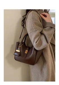 Detailed view of a vintage brown leather handbag with gold hardware and a matching charm