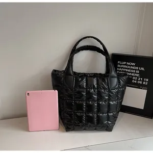 Dettaglio di una borsa tote trapuntata nera che mostra la capienza con un tablet