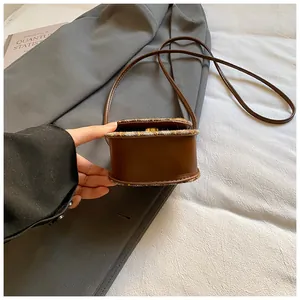 Close-up of mini vintage tweed and brown leather crossbody bag held by hand