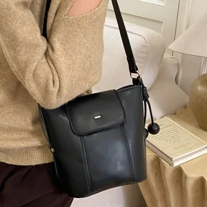 Classic black leather bucket bag with adjustable shoulder strap and gold metallic pendant