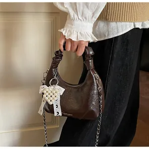 Detail of dark brown hobo bag with pleated texture and pearl heart charm accessory