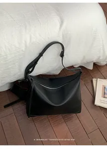Detail of black lychee grain leather tote bag with a minimalist top zipper closure