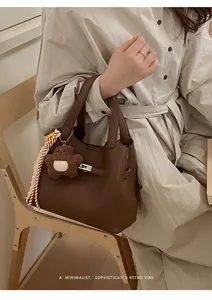 Detail of retro dark brown leather bucket bag with plush bear and striped scarf