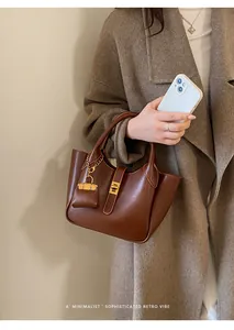 Detail of dark brown minimalist tote with metal lock and matching mini bag charm