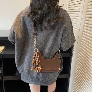 Brown half-moon chain shoulder bag with decorative ethnic beads and golden hardware