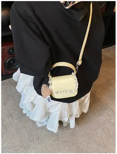 Détail du sac bandoulière jaune avec bords en dentelle et pendentif en forme de cœur