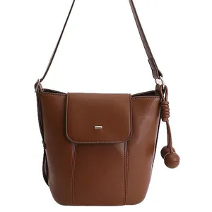 Brown oil-wax leather bucket bag with silver buckle and decorative sphere charms