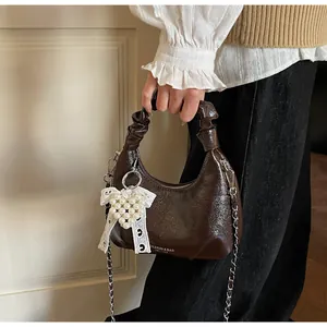 Detailed view of dark brown glossy hobo bag with cloud pleats and pearl heart charm