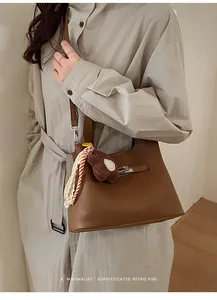 Brown litchi grain leather bucket bag with plush bear charm and silk scarf detail