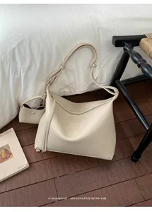 Chic beige hobo tote bag with adjustable strap and matching mini pouch on a retro chair