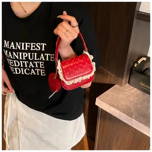 Détail du sac à main rouge à pois avec bordure en dentelle et breloque coeur en peluche