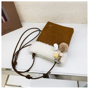 Détail du sac bandoulière d'hiver avec bordure en peluche et pendentifs décoratifs chic
