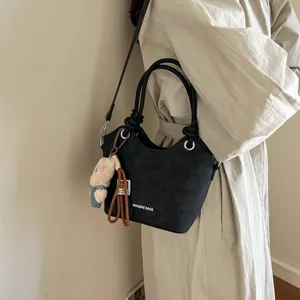 Classic black bucket handbag with adjustable shoulder strap and cute plush charm pendant