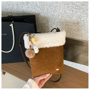 Détail du mini sac bandoulière en daim marron avec bordure en peluche et pendentifs