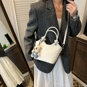 White leather bucket bag with top handle, crossbody strap and a cute plush bear charm