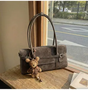Detail of vintage brown suede shoulder bag with plush bear charm and metallic buckle