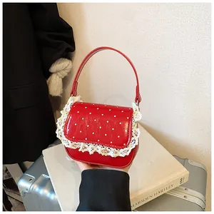 Détail d'un sac à main rouge à pois avec bordure en dentelle blanche sur un livre