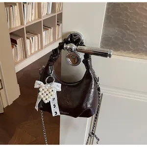 Detail of a dark brown pleated leather bag with silver chain and lace heart charm