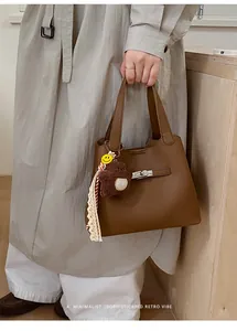 Detailed shot of retro dark brown lychee leather bucket bag with silver lock and charms