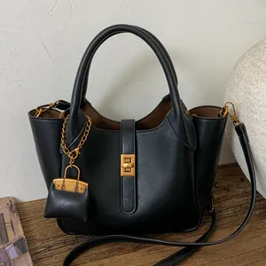Minimalist black leather tote bag with vintage gold twist lock and mini charm detail