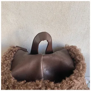 Close-up of brown leather handbag featuring plush faux fur trim and durable handle stitching