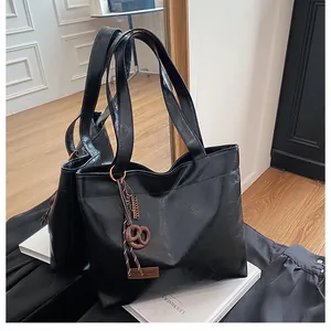 Détail du sac cabas en similicuir noir avec un charmant pendentif en forme de bretzel