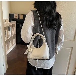 Detail of white pleated handle handbag with silver chain and heart pearl charm