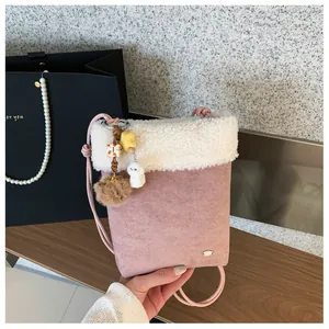 Gros plan du mini sac bandoulière en daim rose avec bordure pelucheuse et jolis grigris