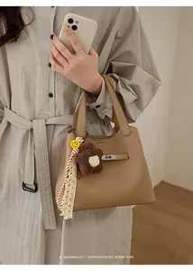 Close-up of retro khaki bucket bag with lychee texture leather and cute bear pendant