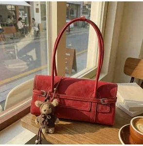 Detail of red suede tote bag with leather straps and a cute brown knitted bear charm