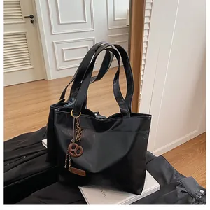 Détail d'un sac cabas en cuir noir avec un charm de mode unique en forme de bretzel brun