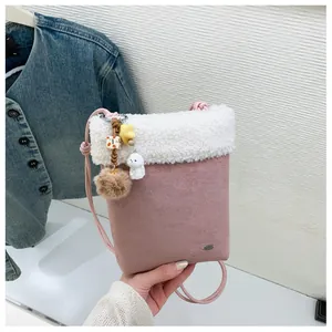 Détail du sac bandoulière rose en suédine avec bordure en polaire blanche et breloques peluches