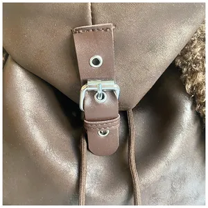 Detail of brown leather backpack with silver buckle and plush faux fur trim detail