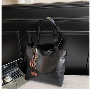 Détail du cabas en cuir noir froissé avec finition brillante et pendentif mode