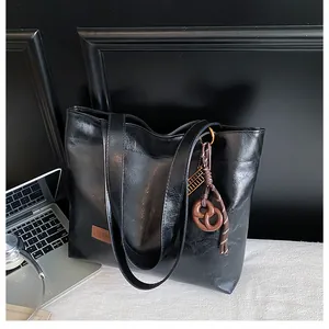 Détail d'un cabas noir brillant avec étiquette de mode marron et breloque biscuit