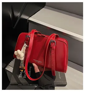 Detail of red glossy leather tote bag with white flower charm and silver buckle straps