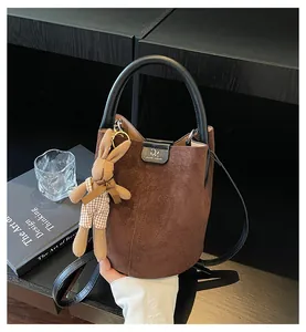 Detail of a brown suede bucket bag featuring a rabbit pendant and black leather accents