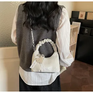 Detail view of white ruched leather crossbody bag with heart pearl charm and lace bow
