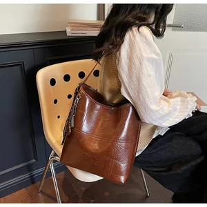Details der braunen Bucket Bag aus geöltem Wachsleder mit Kreuzstich und Logo-Prägung