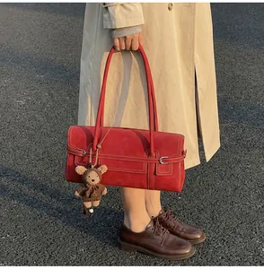 Detail of red suede vintage tote bag featuring contrast stitching and plush bear charm
