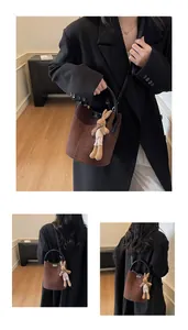 Detail of brown suede bucket bag featuring a black circular handle and cute bunny charm
