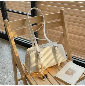 Close-up of a white PU leather tote bag with floral charm on a wooden chair
