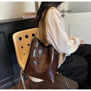 Nahaufnahme der braunen Wachsleder-Beuteltasche mit Logo-Prägung und Quasten-Anhänger