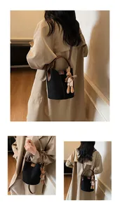 Detail of black suede bucket bag with brown leather strap and cute rabbit pendant charm