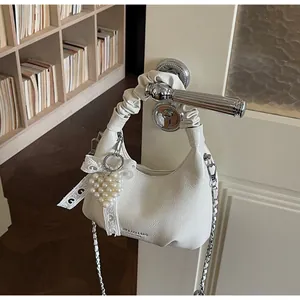 Detail of white textured leather mini bag with lace bow and pearl heart charm accessory