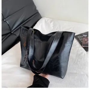 Gros plan détaillé du sac cabas en cuir noir brillant avec breloque tressée