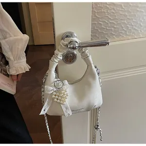 Detail of cream hobo bag with pleated handle, silver chain, and pearl heart charm