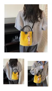 Detail of yellow suede bucket bag with DM logo and brown plush rabbit doll charm